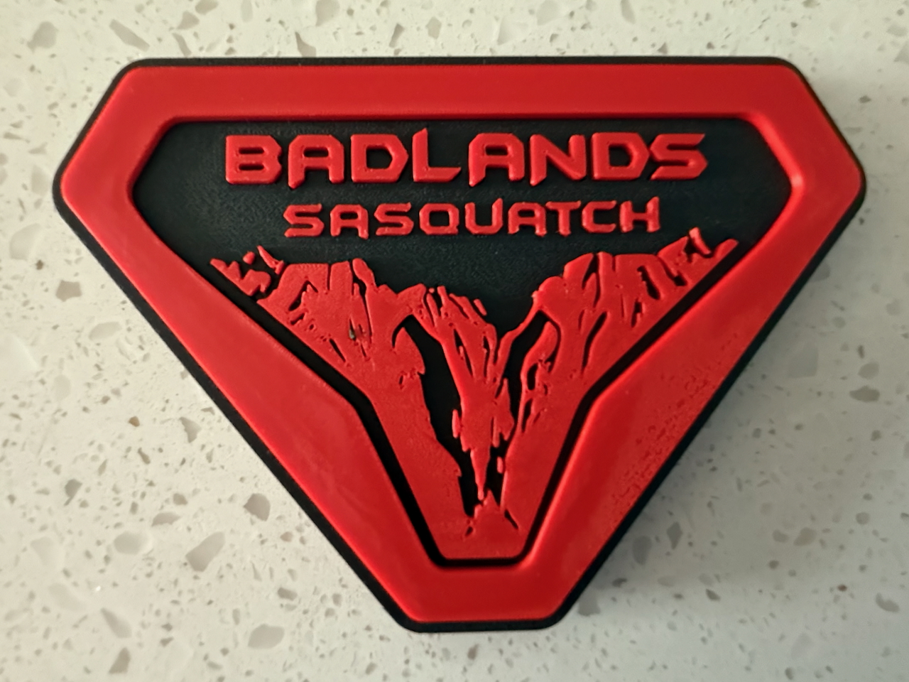 Black and white Badlands badges showing front and back